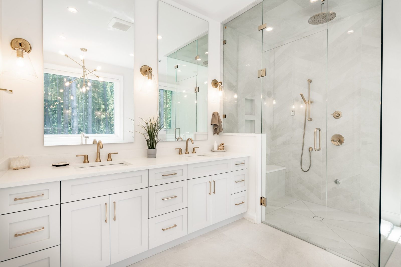 Frameless glass shower and custom vanity mirrors in a white marble bathroom